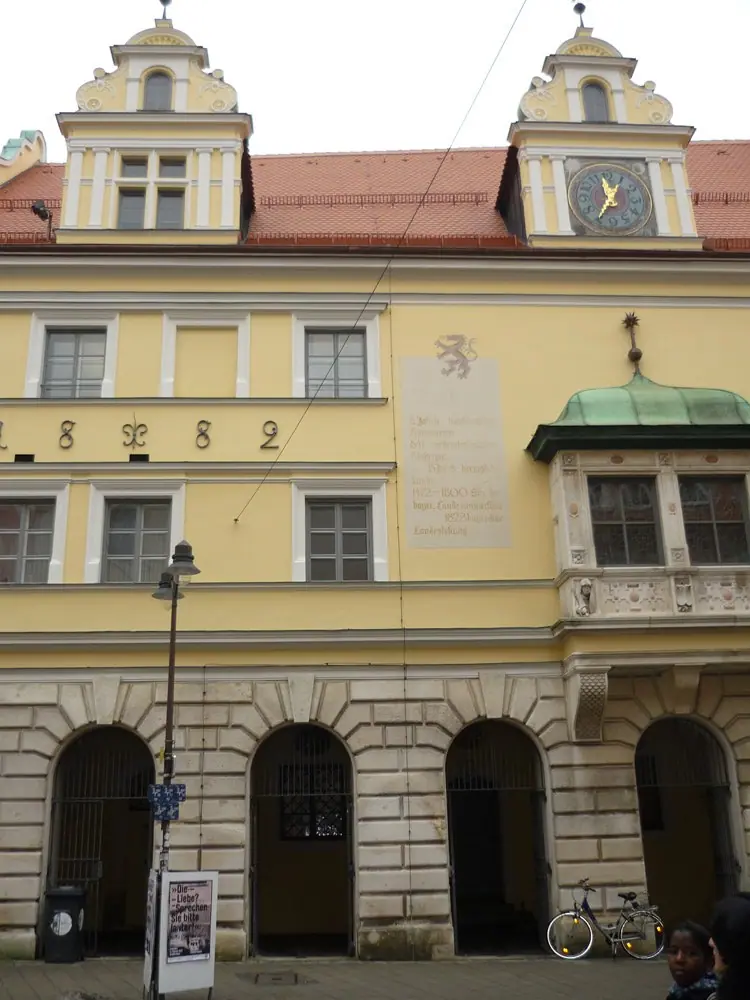 Gelbe Rathausfassade mit Erker, Uhr und Dachgauben über Rundbogenarkaden
