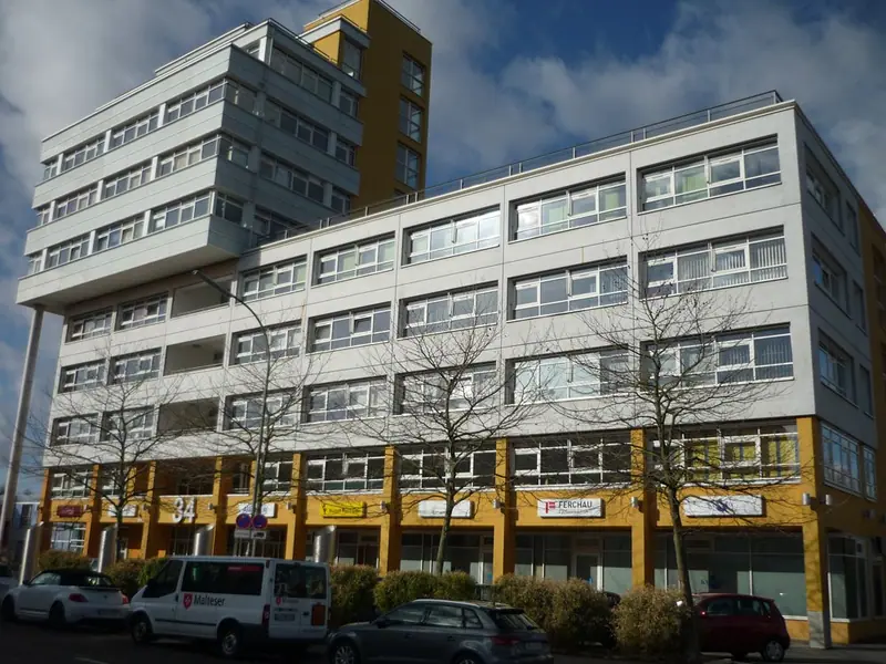 Mehrgeschossiger Gebäudekomplex mit weißen und gelben Fassadenflächen und Fensterbändern